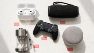 Flat lay of tech gadgets with price tags — wireless earbuds, portable speaker, game controller, espresso machine and smart speaker